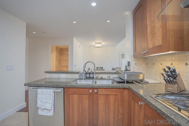 kitchen with appliances with stainless steel finishes, dark stone counters, decorative backsplash, sink, and kitchen peninsula