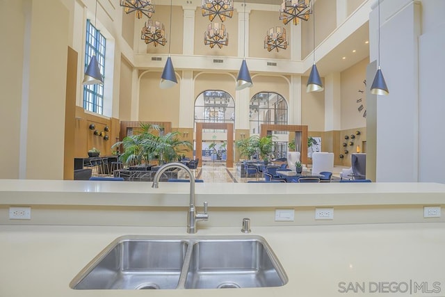 kitchen featuring decorative light fixtures, a towering ceiling, and sink