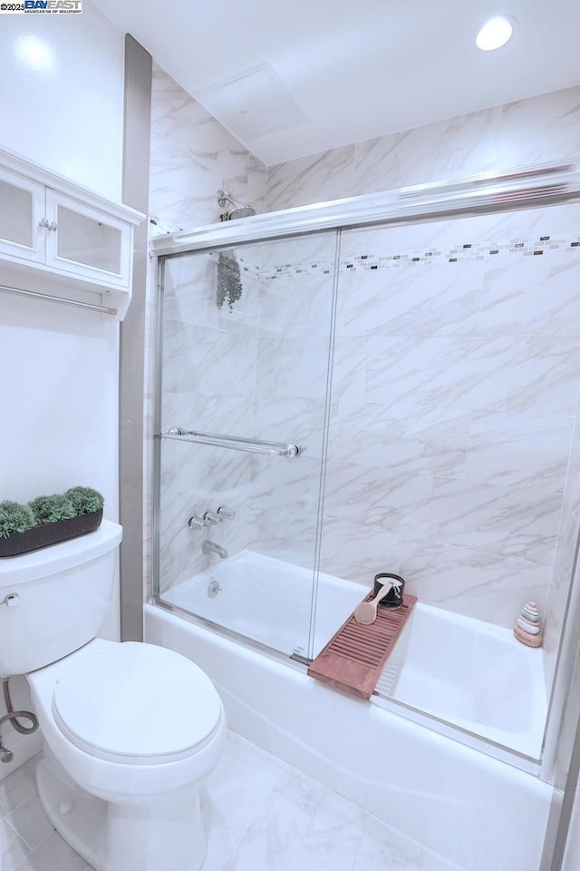 bathroom with toilet and shower / bath combination with glass door