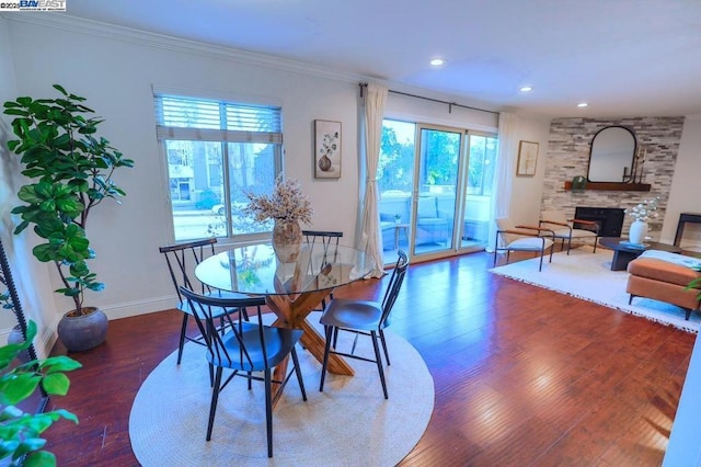 dining area with crown molding, a fireplace, a wealth of natural light, and dark hardwood / wood-style flooring