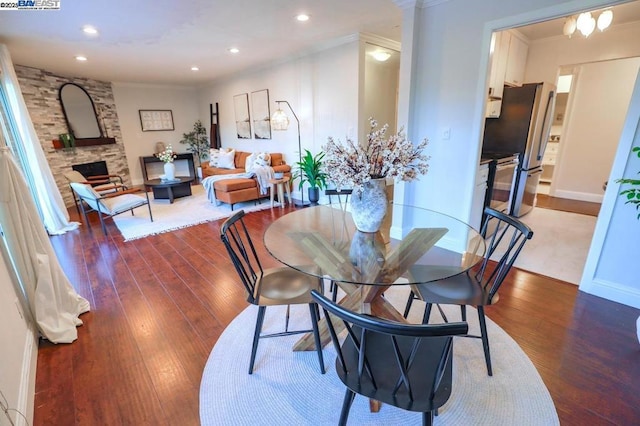 dining room with ornamental molding, dark hardwood / wood-style floors, and a stone fireplace