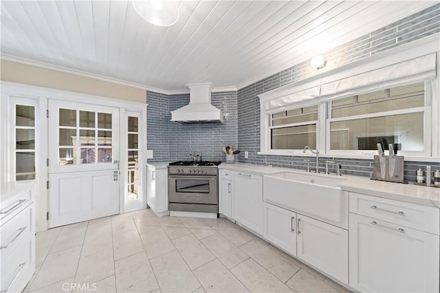 kitchen featuring sink, stainless steel stove, white cabinets, and custom exhaust hood