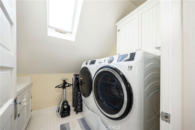 washroom featuring a skylight, washing machine and clothes dryer, and cabinets