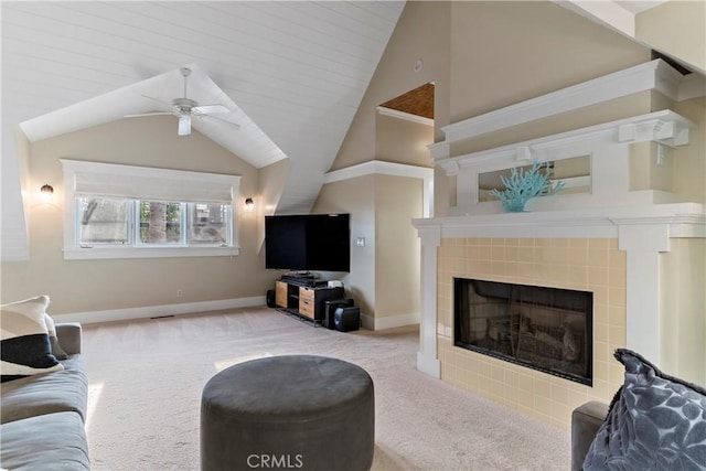 living room with ceiling fan, light carpet, a tiled fireplace, and vaulted ceiling