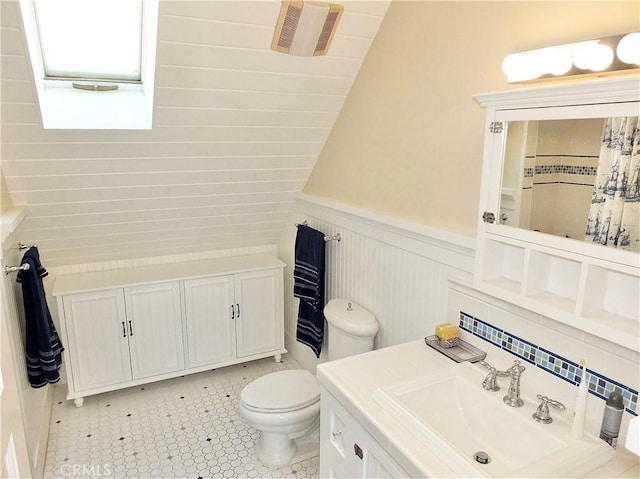 bathroom featuring toilet, vanity, tile patterned flooring, walk in shower, and lofted ceiling