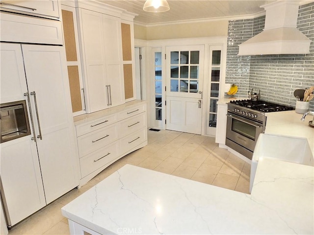 kitchen featuring light stone countertops, stainless steel range, tasteful backsplash, premium range hood, and crown molding