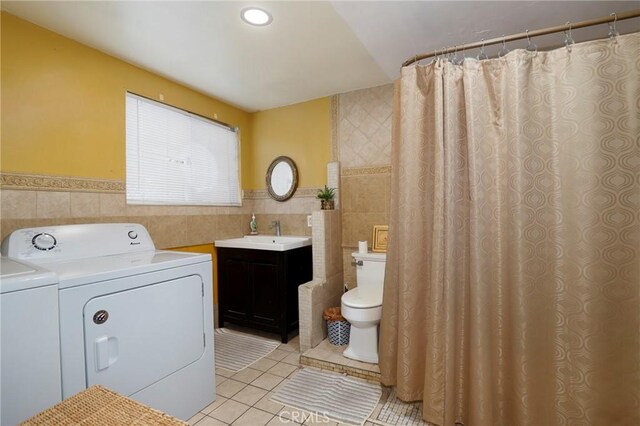 bathroom with tile patterned flooring, vanity, independent washer and dryer, and tile walls