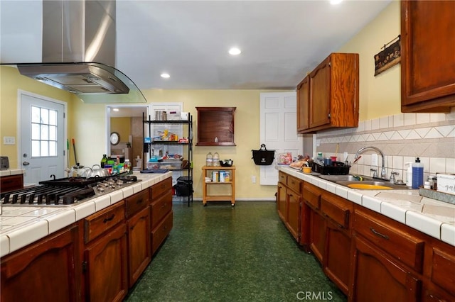 kitchen featuring sink, decorative backsplash, tile countertops, stainless steel gas stovetop, and island range hood