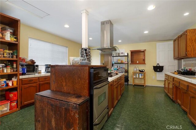 kitchen with tile counters, oven, island exhaust hood, and decorative columns