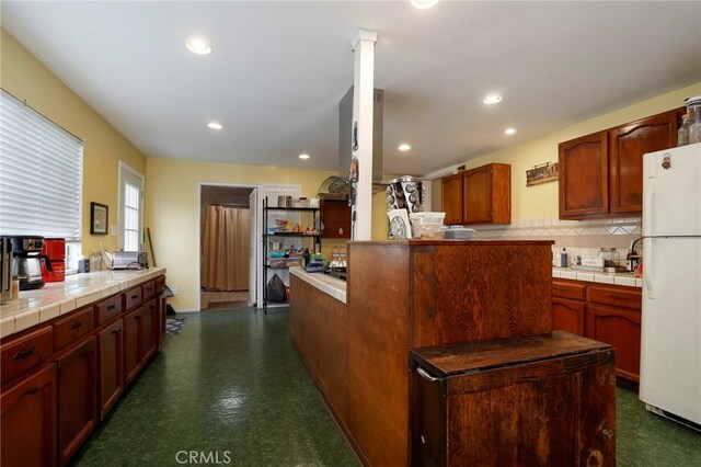 kitchen featuring decorative backsplash, white refrigerator, and tile counters