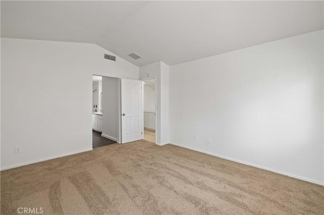 unfurnished bedroom with vaulted ceiling, carpet flooring, and ensuite bath