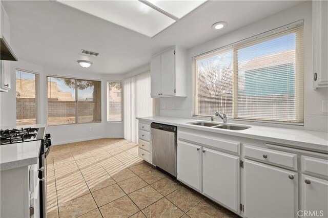 kitchen featuring white gas stove, stainless steel dishwasher, white cabinets, and sink