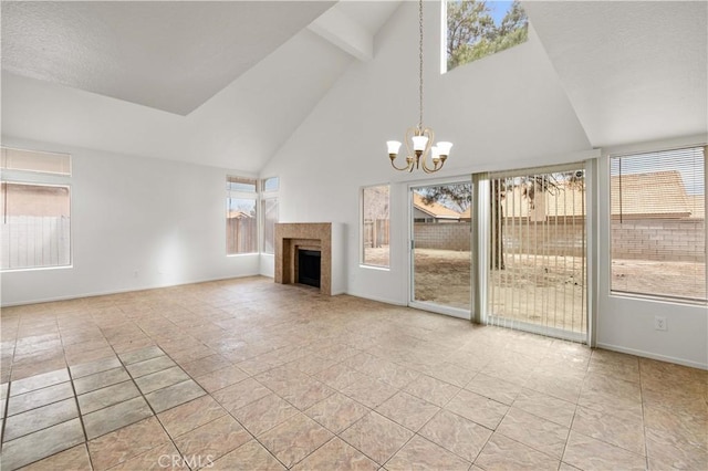 unfurnished living room with light tile patterned floors, a chandelier, a tiled fireplace, and high vaulted ceiling