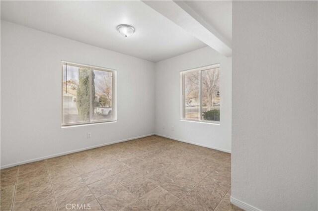 unfurnished room with a healthy amount of sunlight and beam ceiling