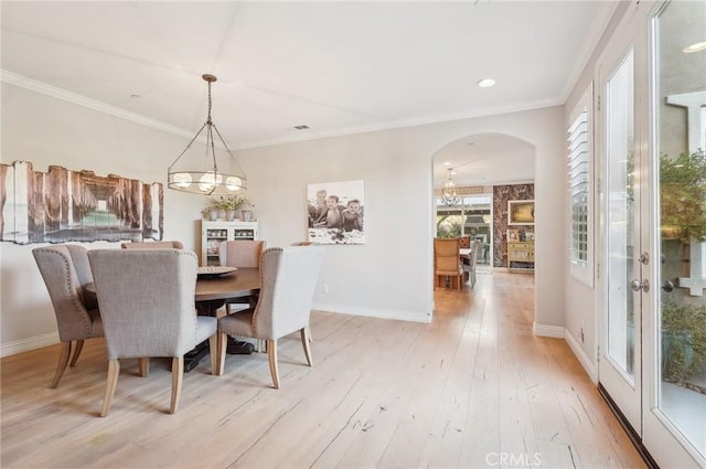 dining area with a wealth of natural light, crown molding, a chandelier, and light hardwood / wood-style flooring