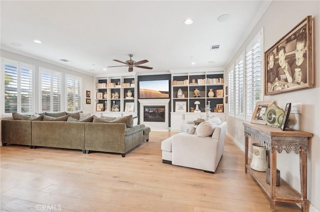 living room with ceiling fan, light wood-type flooring, built in features, and ornamental molding