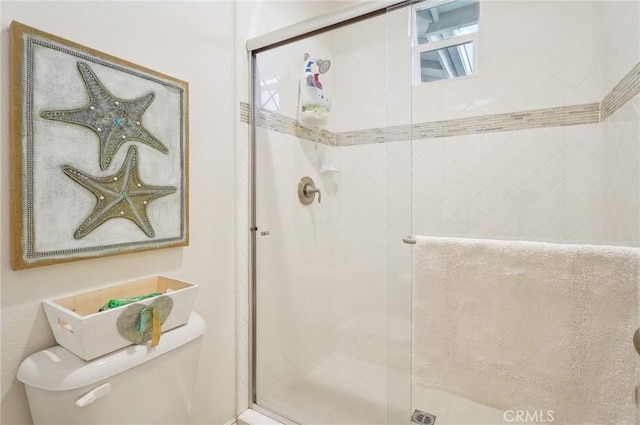 bathroom with toilet and a shower with door