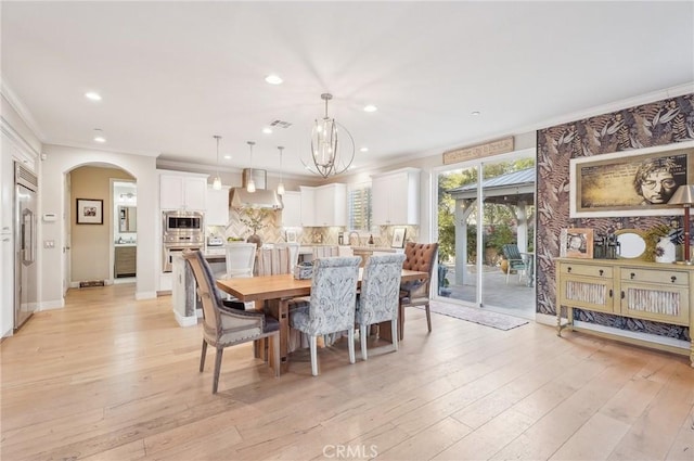 dining area featuring light hardwood / wood-style flooring, crown molding, and a notable chandelier