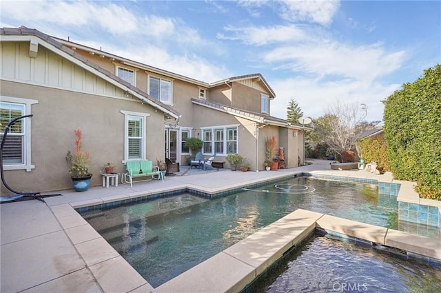 rear view of property featuring a swimming pool with hot tub and a patio