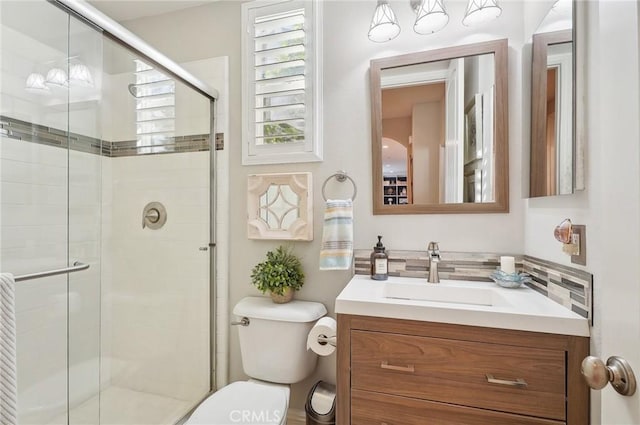 bathroom with toilet, vanity, and a shower with door