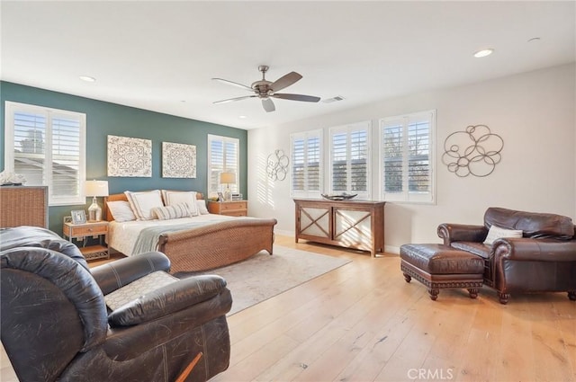 bedroom featuring ceiling fan, light hardwood / wood-style floors, and multiple windows