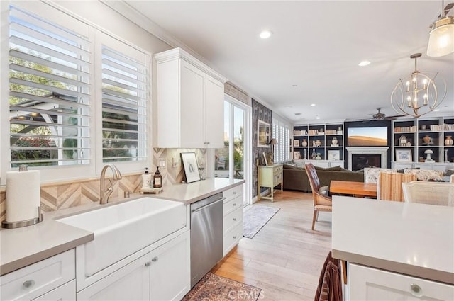 kitchen with decorative light fixtures, white cabinetry, a healthy amount of sunlight, sink, and stainless steel dishwasher