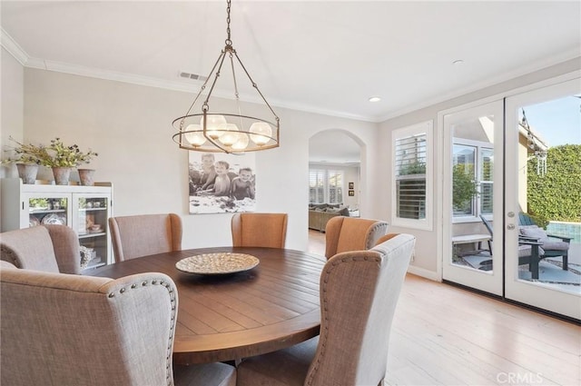 dining space with crown molding, a notable chandelier, and light wood-type flooring