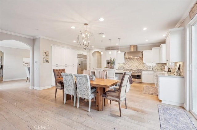 dining room with light hardwood / wood-style flooring, crown molding, and a notable chandelier