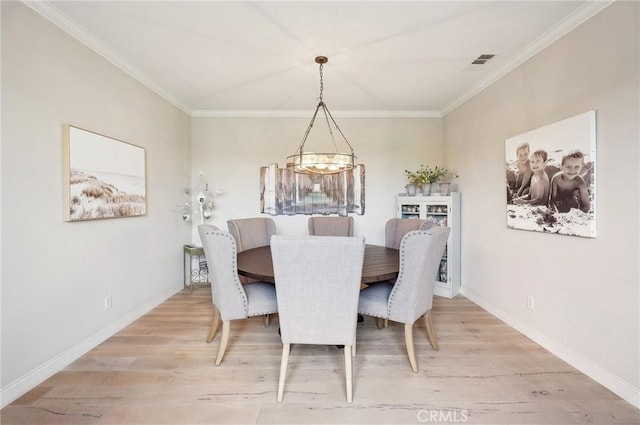 dining room featuring ornamental molding, a chandelier, and light wood-type flooring