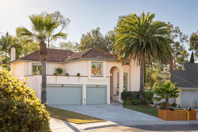 mediterranean / spanish-style house featuring driveway, a tile roof, a garage, and stucco siding