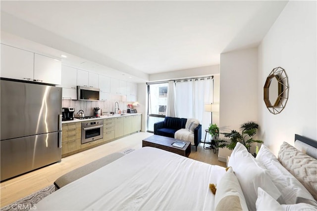 bedroom featuring light wood-type flooring, stainless steel fridge, and sink