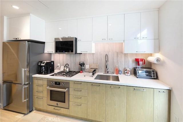 kitchen featuring stainless steel appliances, decorative backsplash, white cabinets, and sink