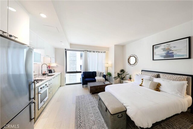 bedroom featuring sink, light hardwood / wood-style flooring, and stainless steel refrigerator