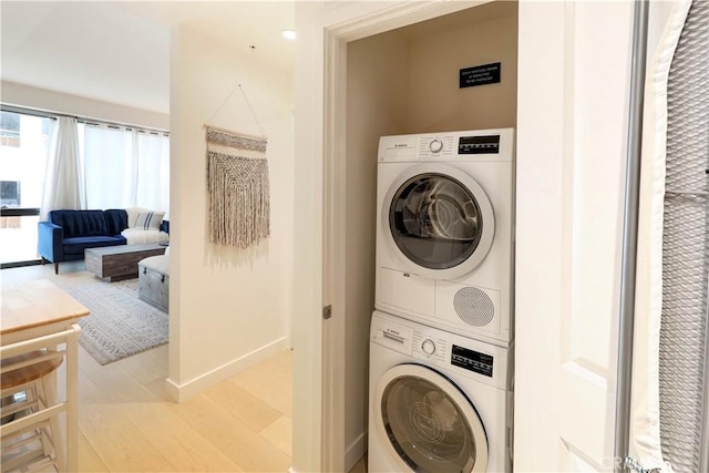 laundry room featuring light hardwood / wood-style floors and stacked washer / dryer