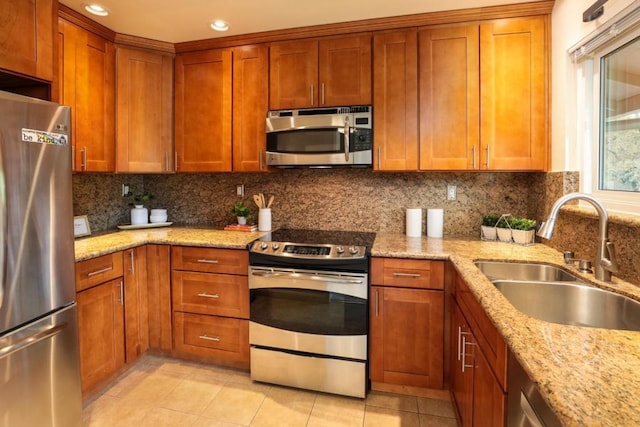 kitchen featuring appliances with stainless steel finishes, tasteful backsplash, light stone counters, sink, and light tile patterned flooring