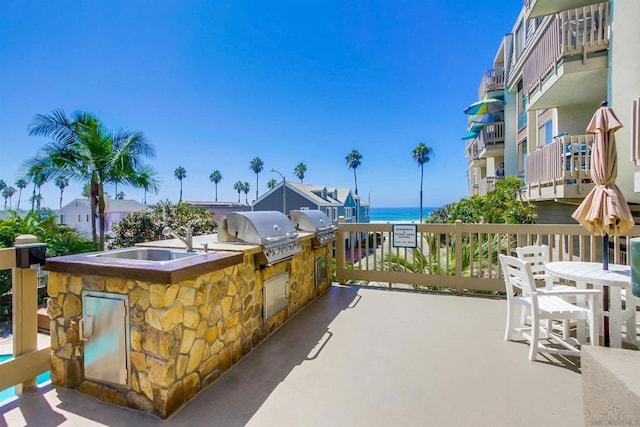 view of patio with area for grilling, a water view, and sink