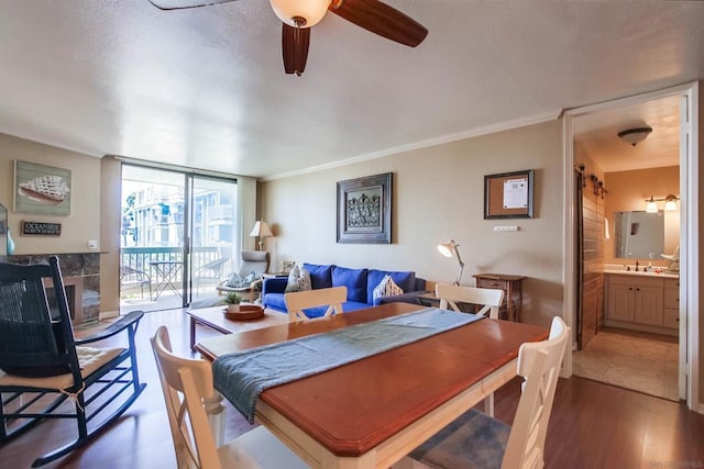 dining area featuring wood-type flooring, sink, ornamental molding, ceiling fan, and expansive windows