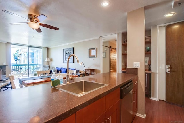 kitchen with a barn door, ceiling fan, dark wood-type flooring, stainless steel dishwasher, and sink