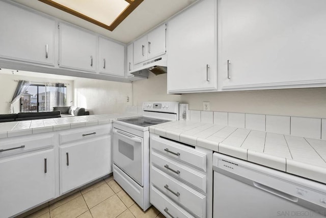 kitchen featuring light tile patterned floors, tile counters, white cabinets, and white appliances