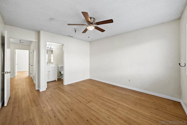 unfurnished bedroom with connected bathroom, ceiling fan, a textured ceiling, and light hardwood / wood-style floors