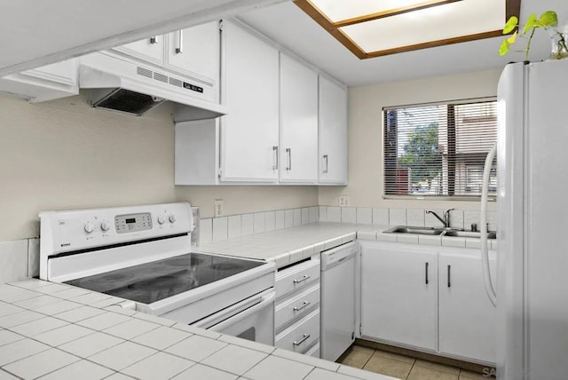 kitchen featuring tile counters, sink, white cabinets, and white appliances