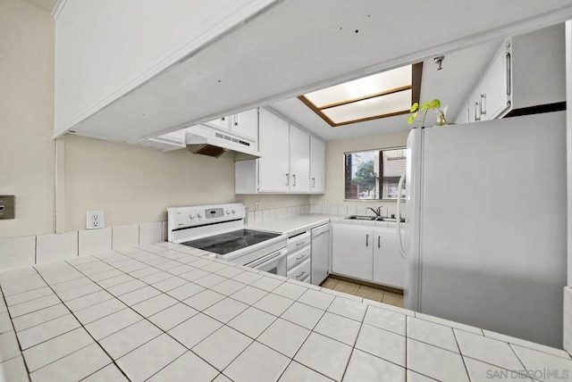 kitchen with tile countertops, sink, white cabinets, and white appliances