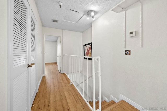 hall featuring light wood-type flooring and a textured ceiling