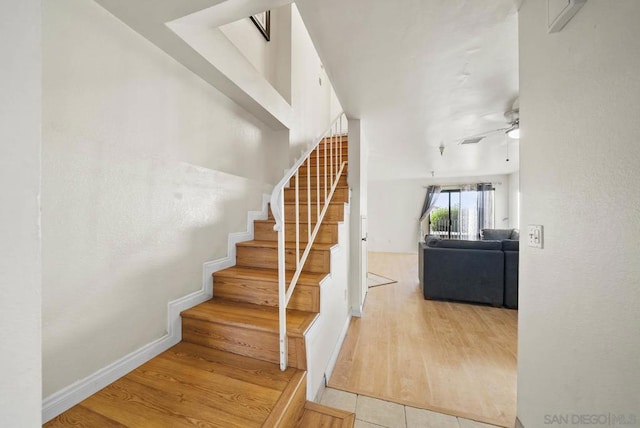 stairs featuring ceiling fan and tile patterned flooring