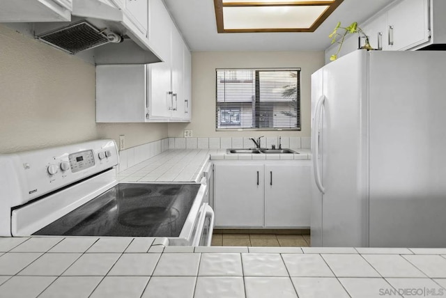 kitchen featuring white cabinetry, white appliances, and tile counters