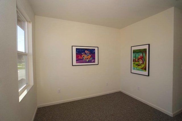 unfurnished room featuring dark colored carpet and plenty of natural light