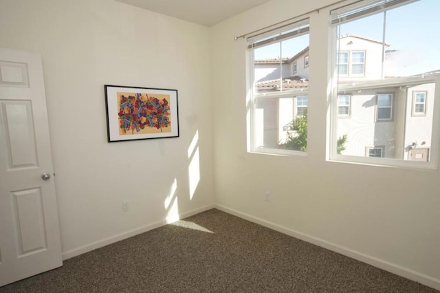 spare room featuring dark colored carpet