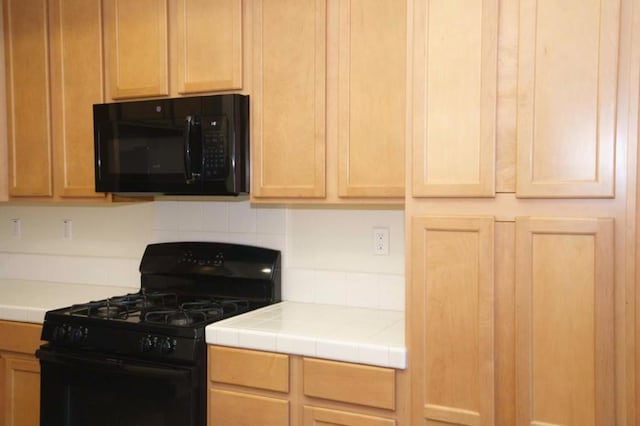 kitchen with light brown cabinets, black appliances, and tile countertops