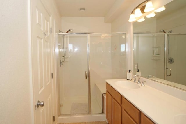 bathroom featuring a shower with door and vanity