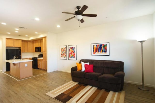 living room featuring wood-type flooring, sink, and ceiling fan